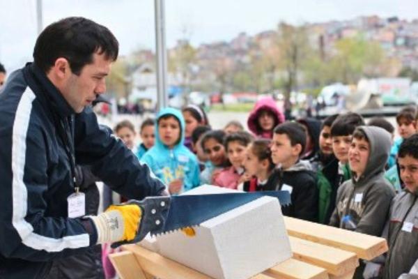 Man holding a saw, showing to youth stakeholders the outcomes of the project through insightful demonstrations